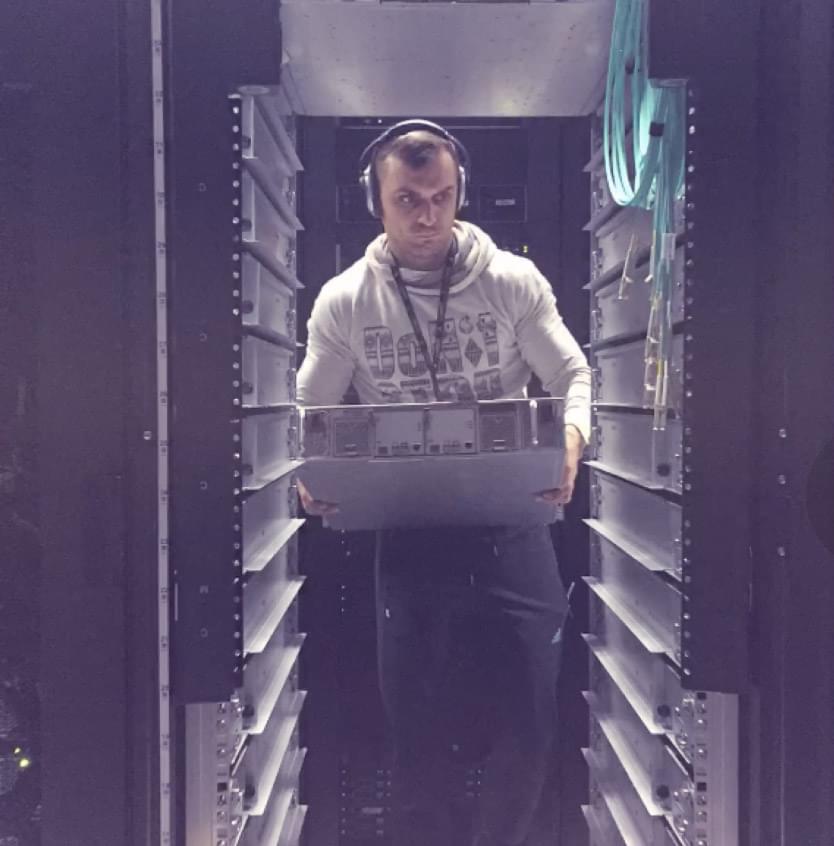 An engineer carrying a server node between two rack rows